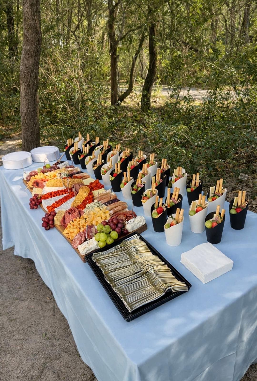 Outdoor charcuterie table spread with individual cups