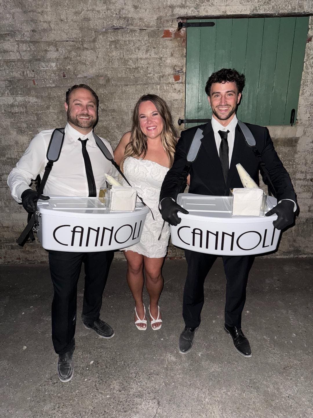 Bride with two cannoli servers at wedding reception