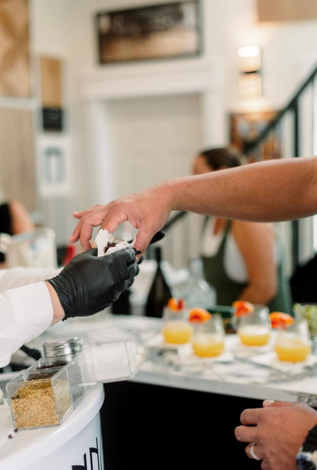 Cannoli being handed to guest with cocktails nearby