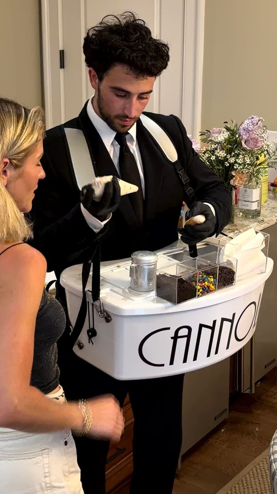 Tuxedoed server filling a fresh cannoli from the cannoli cart