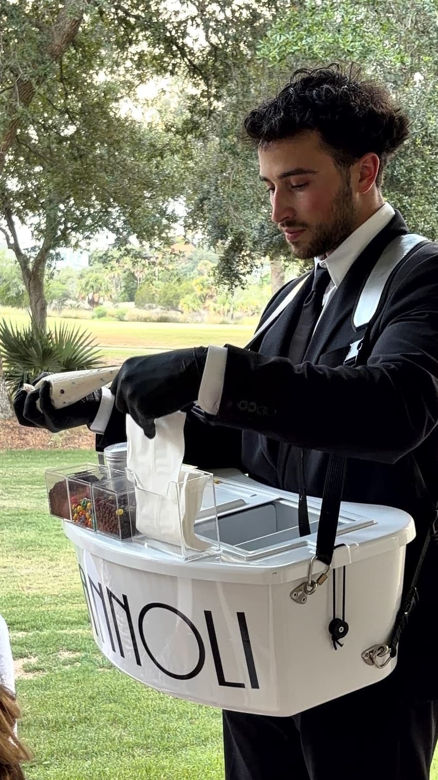 Cannoli server preparing cannoli at an outdoor golf course event