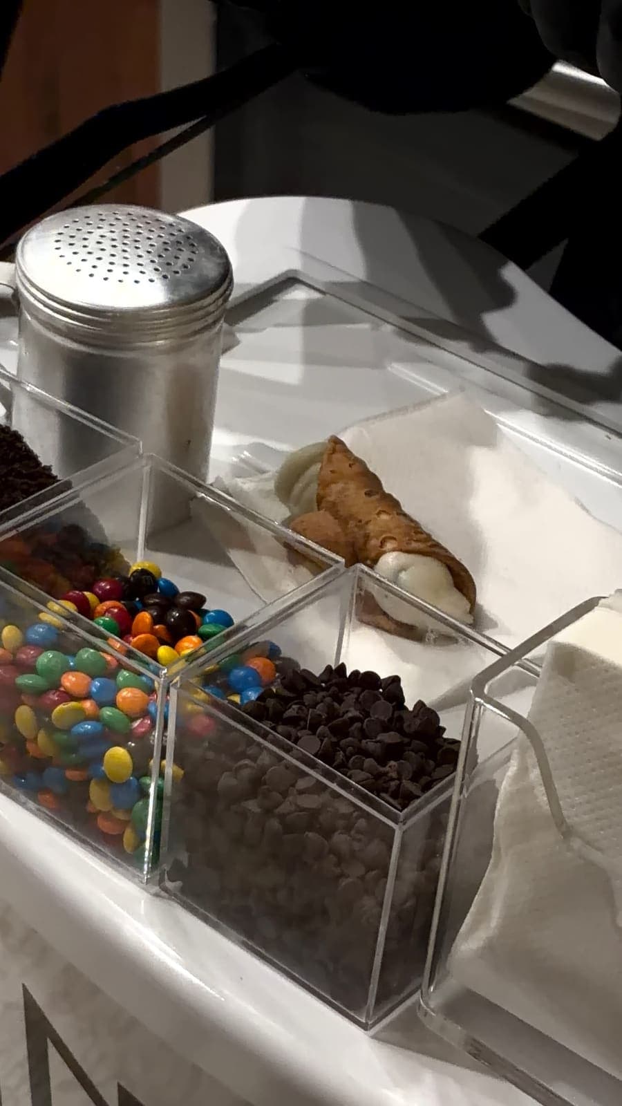 Close-up of cannoli cart toppings with candies and chocolate chips