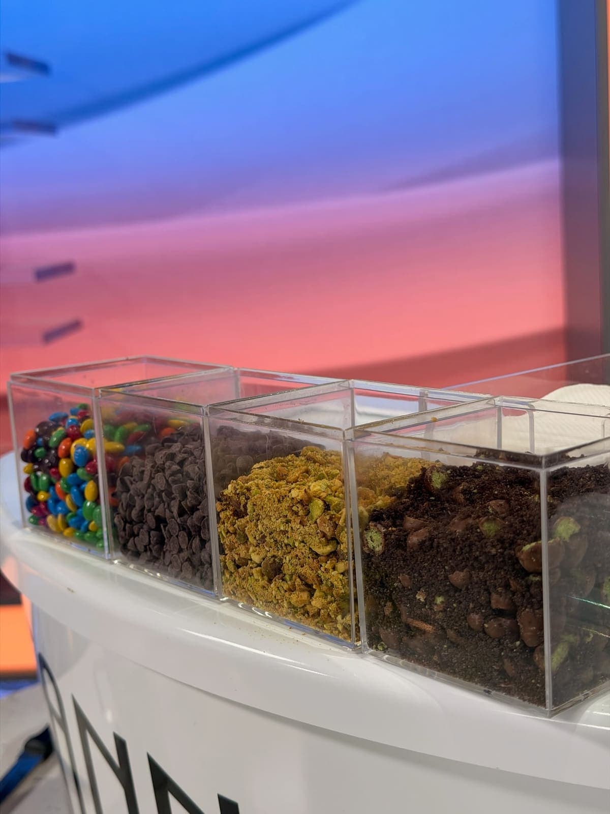 Cannoli topping bins with M&Ms, chocolate chips, and pistachio