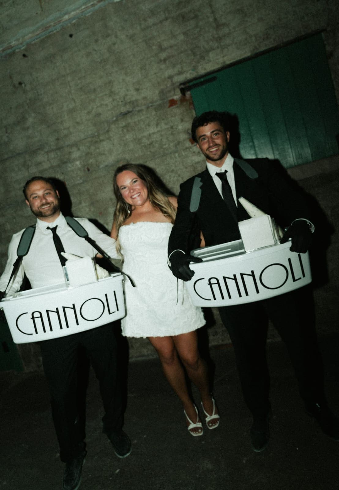 Bride flanked by two cannoli cart servers at a warehouse venue