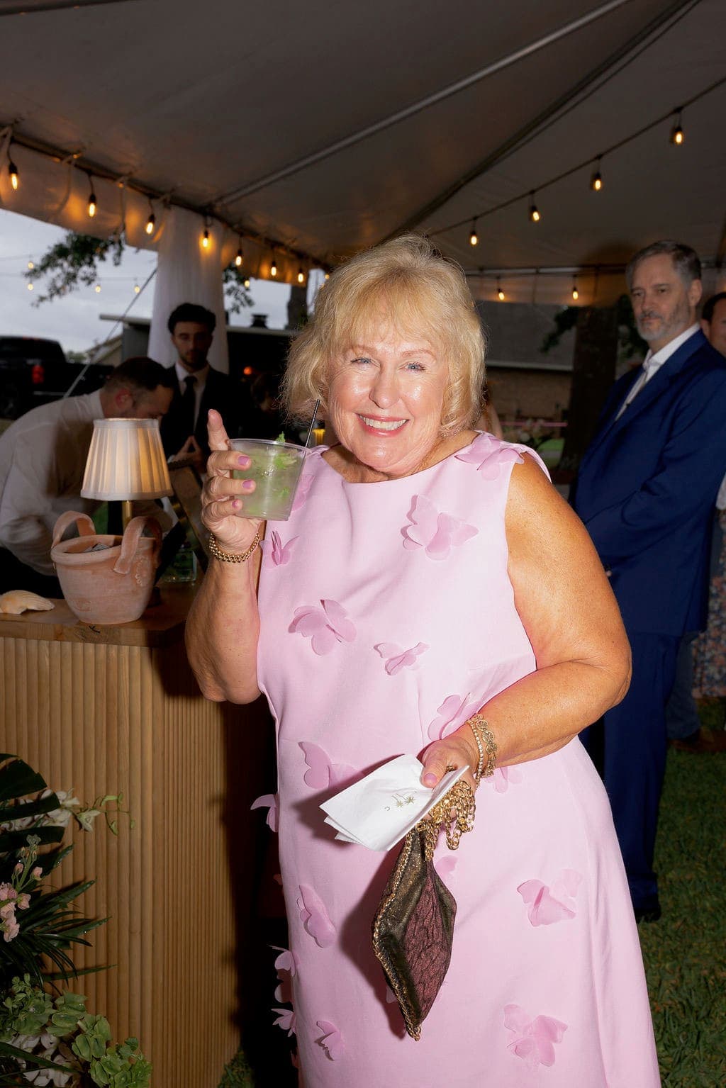 Guest smiling with a fresh mojito at the tent bar