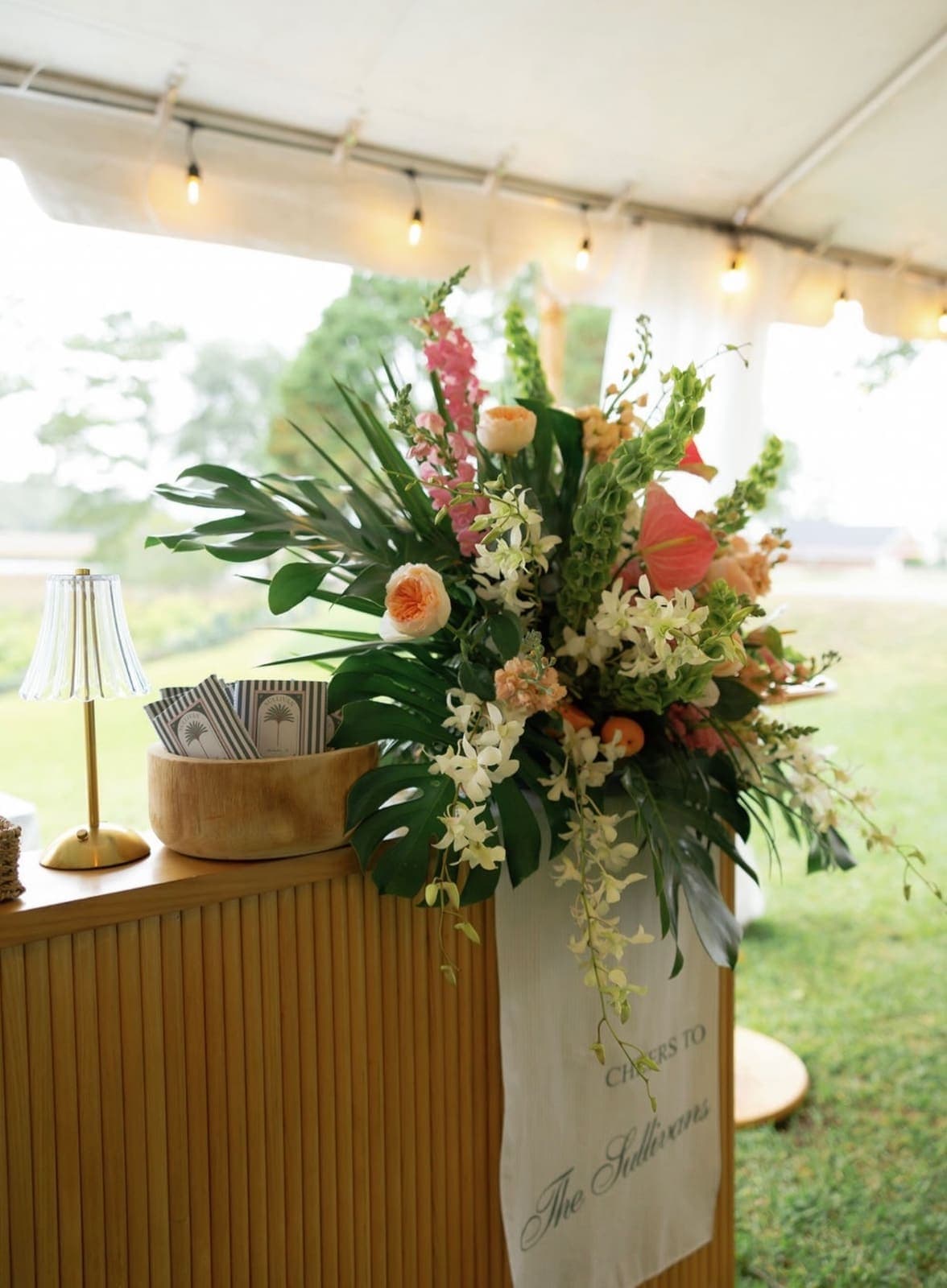 Tropical floral arrangement atop a bamboo bar with custom bar towel
