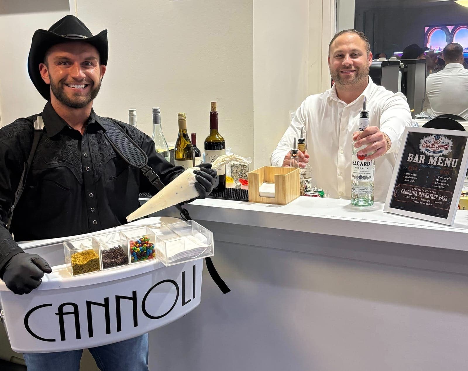 Cannoli server in a cowboy hat beside a bartender at a country event