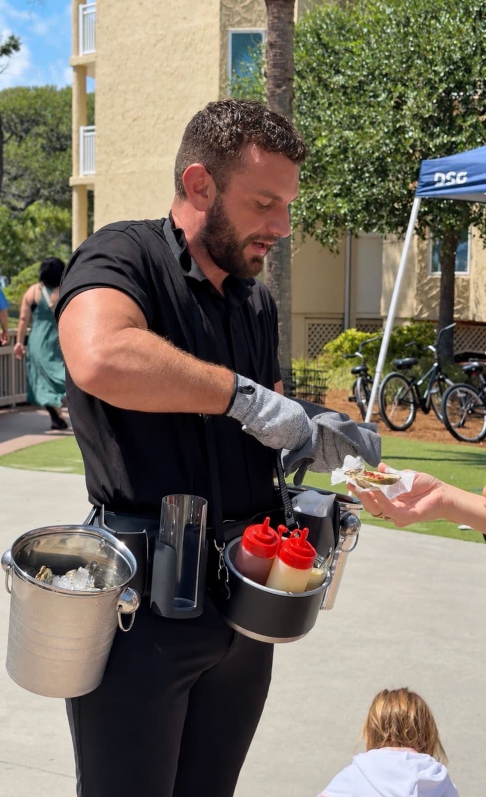 Oyster attendant handing a freshly shucked oyster to a guest
