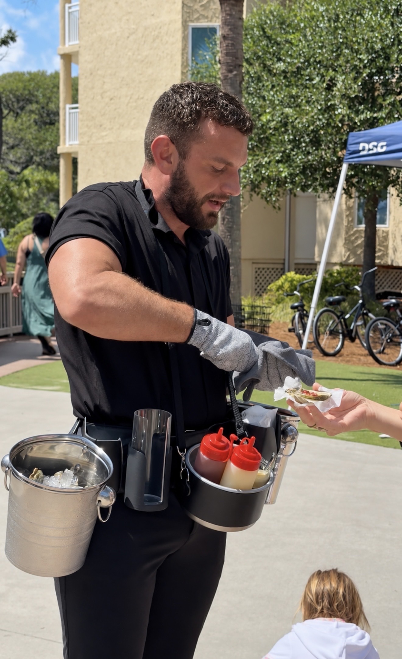 Oyster attendant handing a freshly shucked oyster to a guest